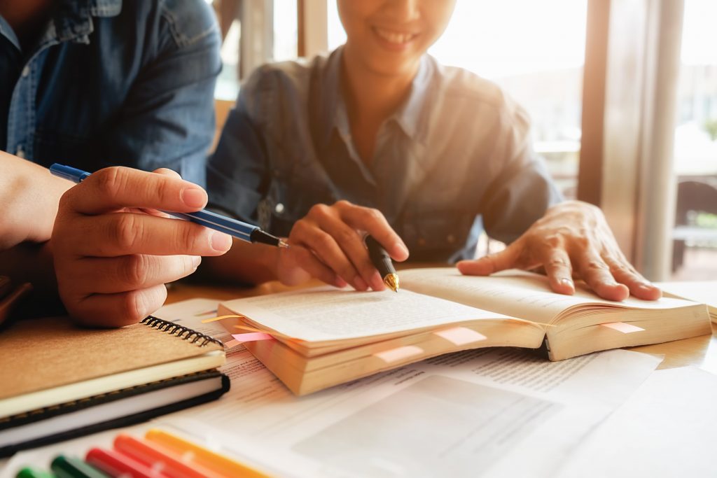 Student Reading Book Studying With Tutor